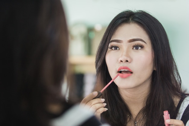 Mooie Aziatische vrouw die lippenstift toepast