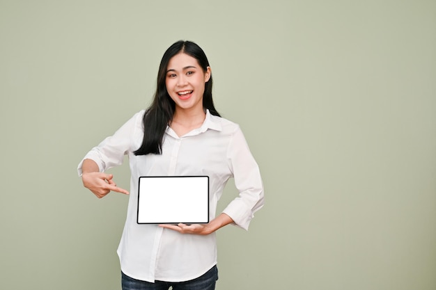 Mooie Aziatische vrouw die met de vinger wijst naar een tabletscherm dat tegen een grijze achtergrond staat