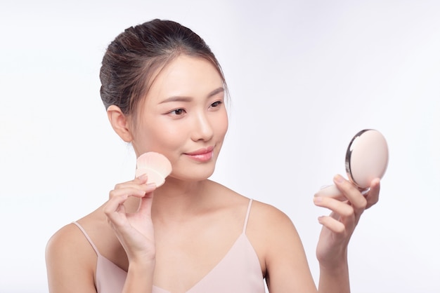 Mooie aziatische vrouw die poederdons toepast op wangmake-up van cosmetica, schoonheid van meisje met gezichtsglimlach