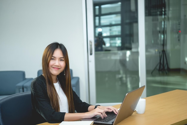 Mooie Aziatische vrouw die 's avonds op kantoor werktThailand werknemer schrijft boek in het bedrijf