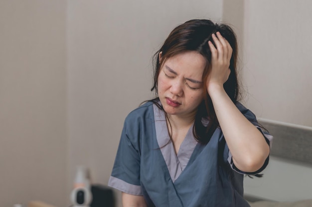 Mooie Aziatische vrouw die stress en hoofdpijn in de slaapkamer draagt