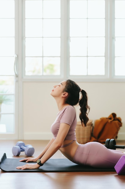 Mooie Aziatische vrouw die thuis sportkleding draagt, terwijl ze naar een tutorial op tablet kijkt