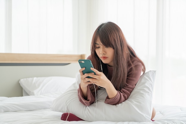 Mooie Aziatische vrouw het spelen smartphone op bed
