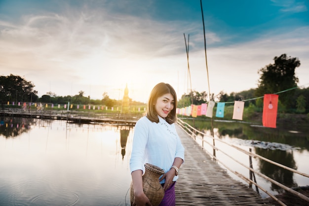 Mooie aziatische vrouw in lokale kledingsholding visserijval die zich op bamboebrug bevinden in ric