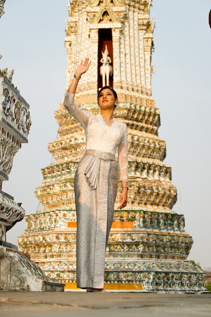 Foto mooie aziatische vrouw in thaise traditionele klederdracht die zeer elite en ouderwetse is. dame in wat-tempel in de openbare ruimte met retro-architectuur voor reistoerisme.