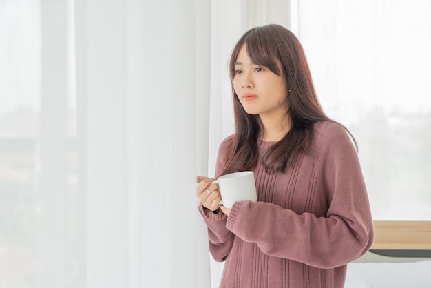 Mooie Aziatische vrouw koffie drinken in de ochtend