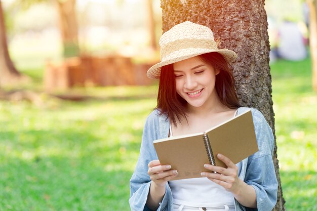 Mooie Aziatische vrouw leesboek in het park op vakantie zelflerend