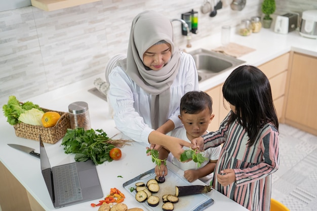 Mooie aziatische vrouw met dochter en zoon die diner koken tijdens ramadan voor iftar die het vasten breekt