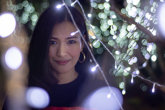 Foto mooie aziatische vrouw op een achtergrond met bokehkleurenlichten