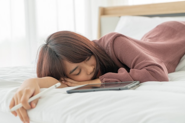 mooie Aziatische vrouwen die met tablet op bed werken