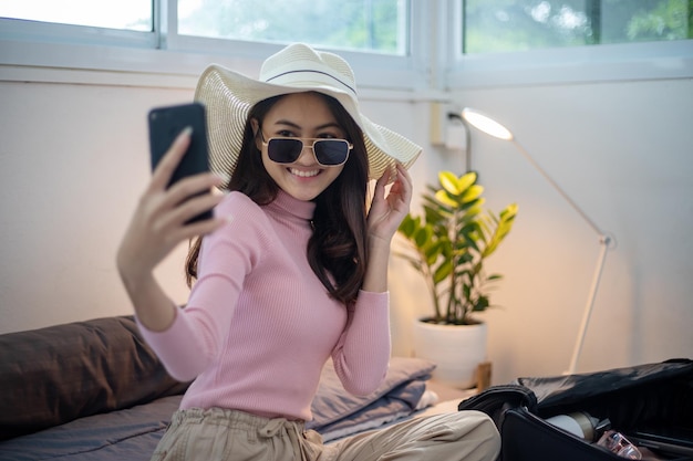 Mooie aziatische vrouwen die smartphone selfie gebruiken en koffers inpakken voor reizen