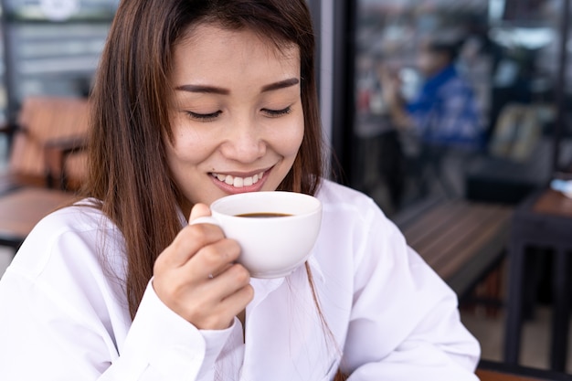 Mooie aziatische vrouwen drinken koffie of thee in ontspanning. vrouwen zijn blij en genieten in de coffeeshop. rust en ontspanning concept