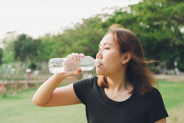 Mooie Aziatische vrouwen drinken water na het trainen om de kern te vernieuwen van het verliezen van lichaam