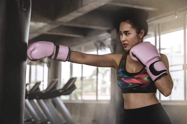 Foto mooie aziatische vrouwen slaan zandzakken in de sportschool