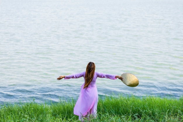 Foto mooie aziatische vrouwen vietnam kijken naar de rivier en hoed traditionele ao dai. concept gevoel ontspannen en gelukkig