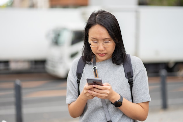 Mooie Aziatische vrouwenreiziger gebruikt een smartphone in het stadscentrum om te zoeken