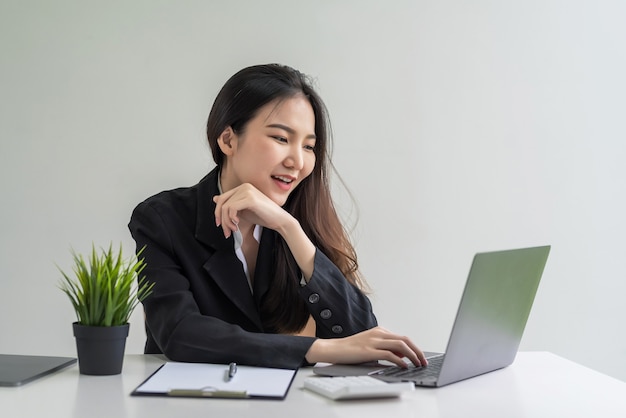 Mooie Aziatische zakenvrouw die met laptop op kantoor werkt.