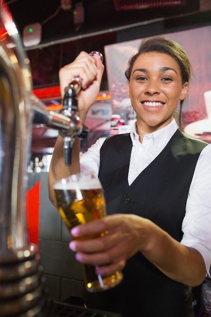 Mooie barvrouw die pint bier trekt