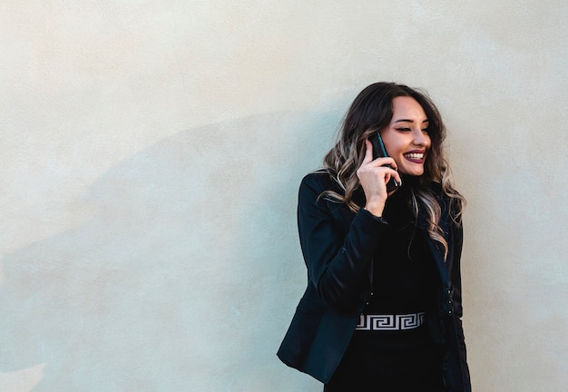 Mooie bedrijfsvrouw buitenshuis met mobiel. Jonge brunette aan de telefoon