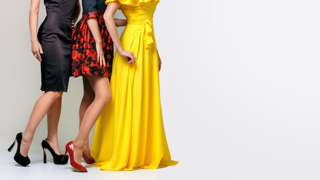 Mooie benen van drie elegante mooie vrouwen, gekleed in jurken en schoenen met hoge hakken
