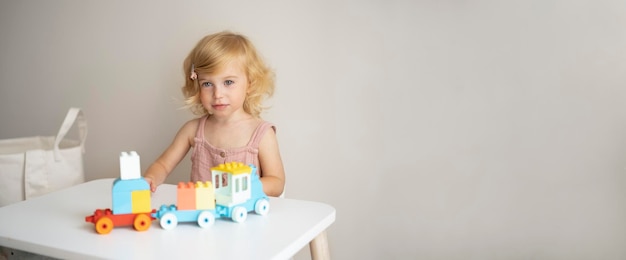 Mooie blanke 1,2-jarige met blond krullend haar die speelt met kleurrijk bouwkubussenspeelgoed