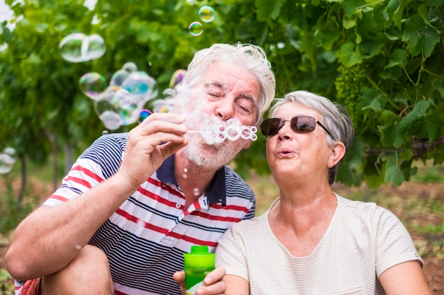 mooie blanke volwassen paar man en vrouw doen zeepbellen samen om te spelen en plezier te hebben met vreugde, buiten natuur locatie voor gelukkige vrijetijdsbesteding voor gepensioneerden met levensstijl