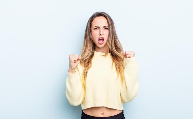 mooie blanke vrouw die agressief schreeuwt met een boze uitdrukking of met gebalde vuisten om succes te vieren