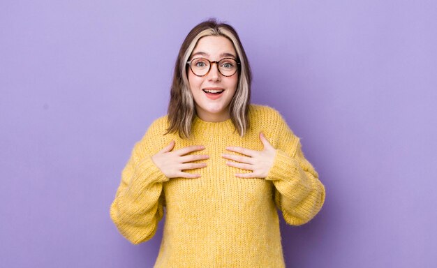 Mooie blanke vrouw die blij verrast, trots en opgewonden naar zichzelf wijst