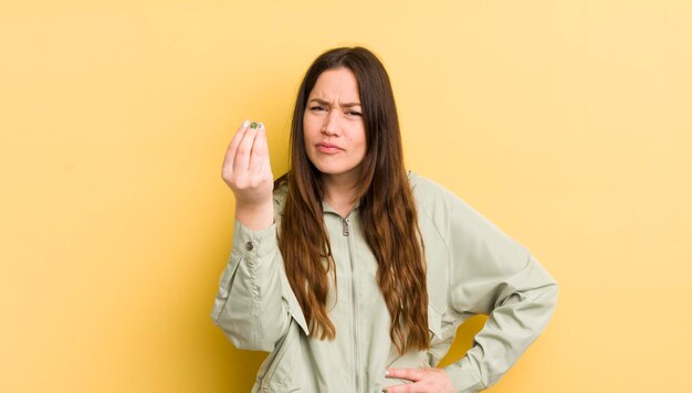 Foto mooie blanke vrouw die capice of geldgebaar maakt en je vertelt om je schulden te betalen