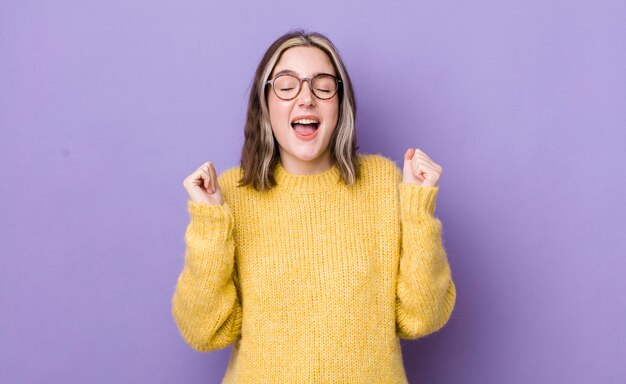 Mooie blanke vrouw die er buitengewoon blij en verrast uitziet en succes viert, schreeuwend en springend