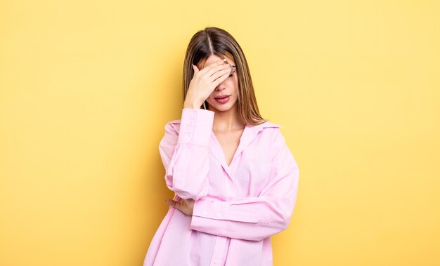 Mooie blanke vrouw die er gestrest uitziet, beschaamd of overstuur is met hoofdpijn die het gezicht bedekt met de hand