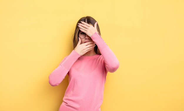 Mooie blanke vrouw die gezicht bedekt met beide handen en nee zegt tegen de camera! foto's weigeren of foto's verbieden