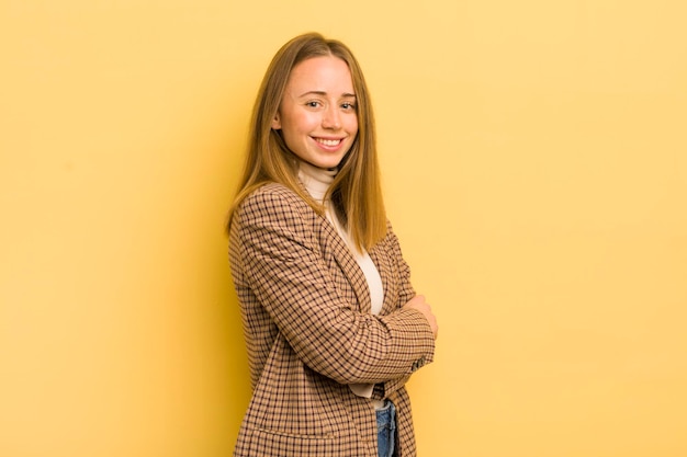 Mooie blanke vrouw die lacht naar de camera met gekruiste armen en een gelukkig zelfverzekerde, tevreden uitdrukking aan de zijkant