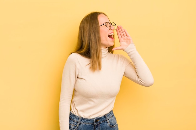 Mooie blanke vrouw die luid en boos schreeuwt om ruimte aan de zijkant te kopiëren met de hand naast de mond