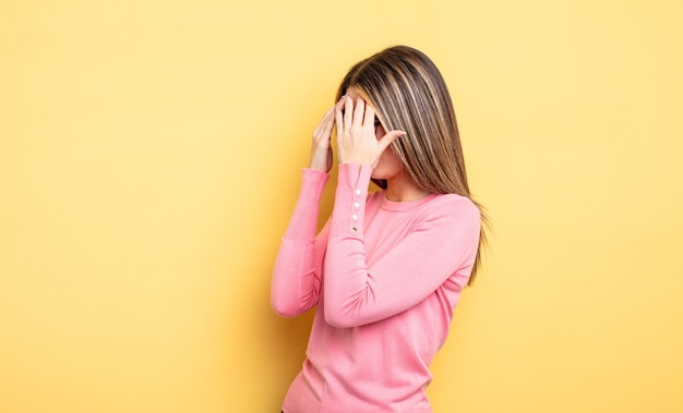 Mooie blanke vrouw die ogen bedekt met handen met een trieste gefrustreerde blik van wanhoop huilend zijaanzicht