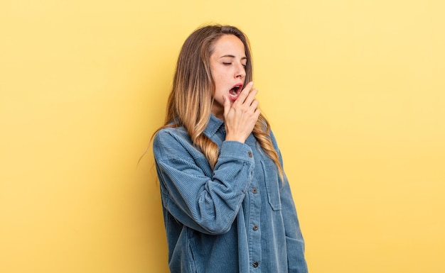 Mooie blanke vrouw die 's ochtends lui gaapt, wakker wordt en er slaperig, moe en verveeld uitziet