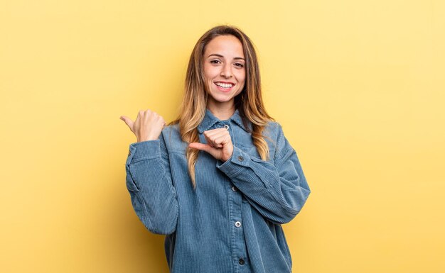 Mooie blanke vrouw die vrolijk en nonchalant lacht en wijst naar de ruimte aan de zijkant, voelt zich gelukkig en tevreden