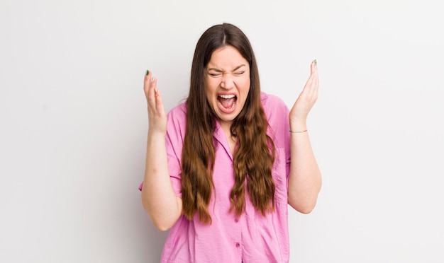 Mooie blanke vrouw die woedend schreeuwt, zich gestrest en geïrriteerd voelt met de handen in de lucht en zegt waarom ik?