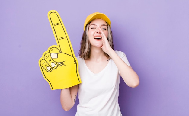 Mooie blanke vrouw die zich gelukkig voelt en een grote schreeuw geeft met handen naast mond nummer één fanhand