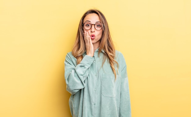 Mooie blanke vrouw die zich geschokt en verbaasd voelt en ongelovig oog in oog staat met wijd open mond