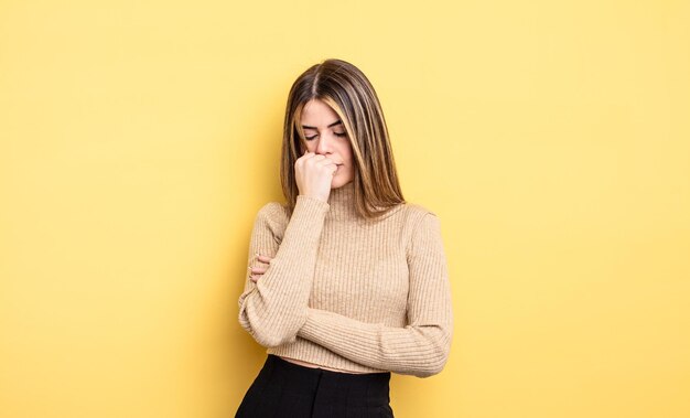 mooie blanke vrouw die zich serieus, attent en bezorgd voelt, zijwaarts starend met de hand tegen de kin gedrukt