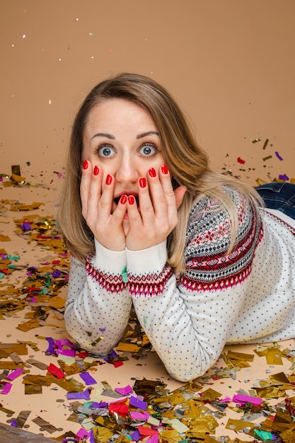 Foto mooie blanke vrouw met golvend blond haar is verrast door iets engs, foto geïsoleerd op bruine muur