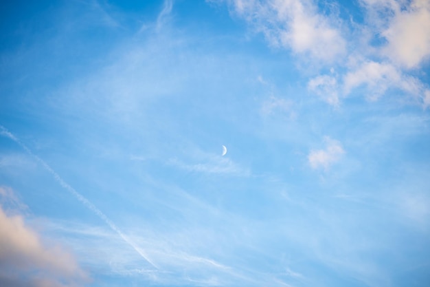 Mooie blauwe lucht met wolken en opkomende maan bij daglicht