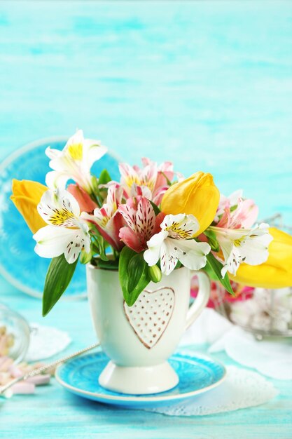 Mooie bloemen in beker op een houten achtergrond kleur