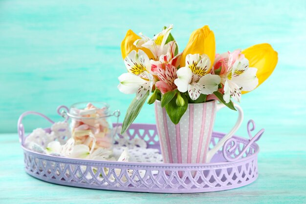 Mooie bloemen in beker op kleur houten tafel