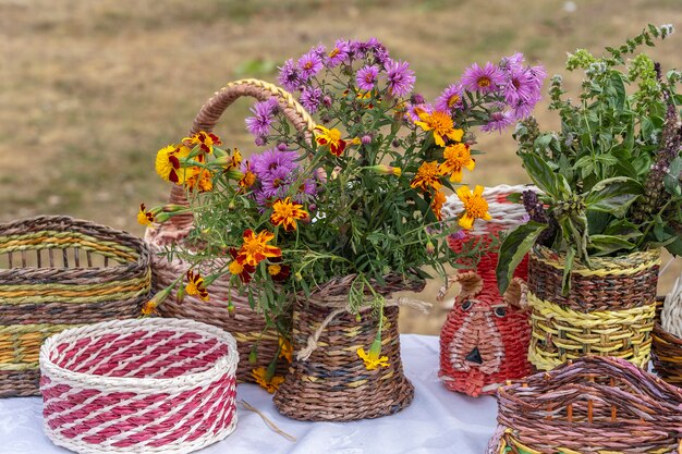 Mooie bloemen in een rieten vaas op een tafel, buiten, close-up. Boeket van violet, paars en oranje bloem. Decoratie van huis. Behang en achtergrond. Tuinieren van Oekraïne