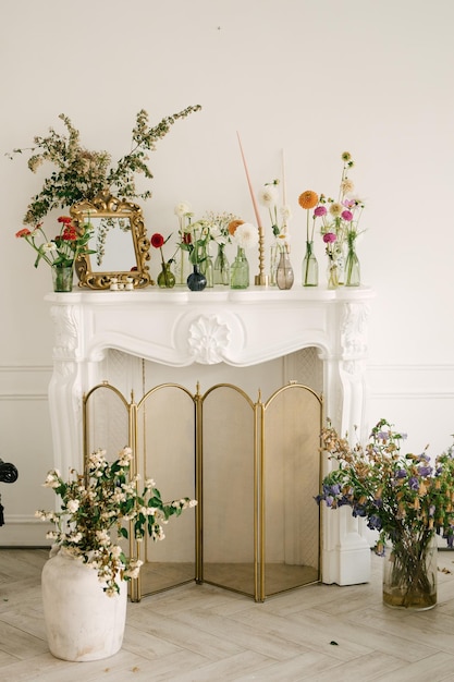 Mooie bloemen in glazen vazen sieren de open haard in huis