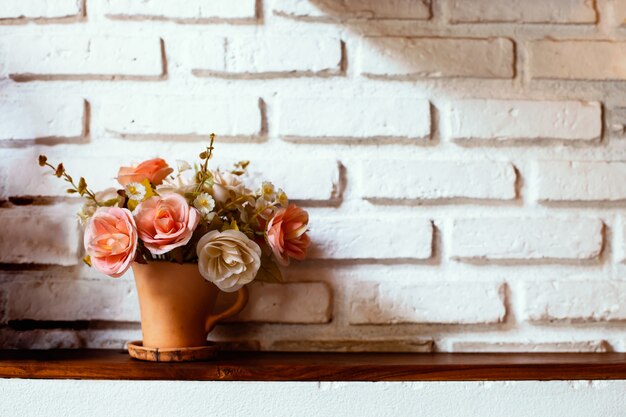 Mooie bloemen in vaas op bakstenen muurachtergrond in uitstekende kleurentoon