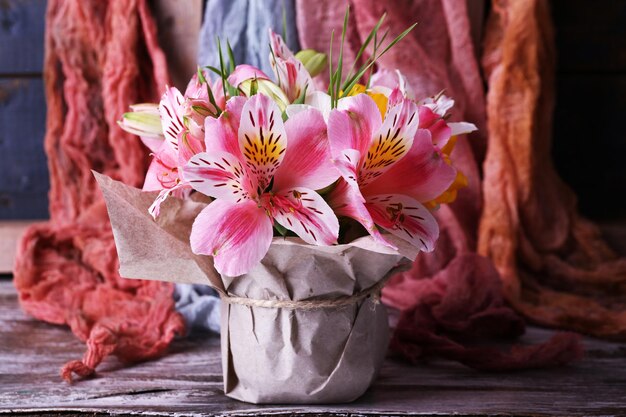 Mooie bloemen in vaas op stoffenachtergrond