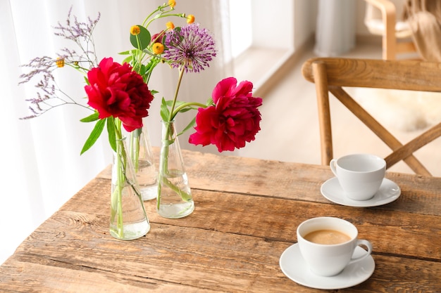 Mooie bloemen in vazen als floraal decor op houten tafel